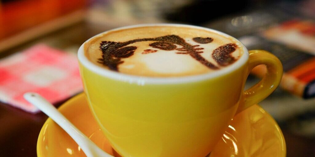 yellow ceramic teacup with cat designed coffee